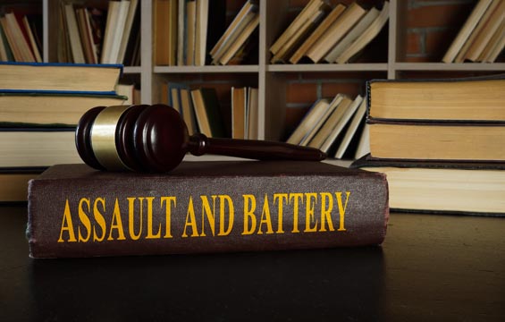 Law book about assault and battery with gavel on top.