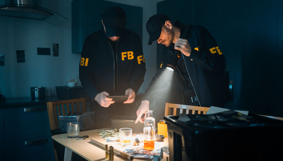 FBI agents with a flashlight during investigation looking at physical evidence on a table at the crime scene