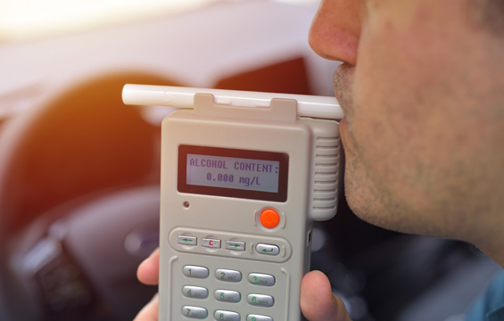 Close-up of driver blowing into a breathalyzer as a test for alcohol content to determine DUI