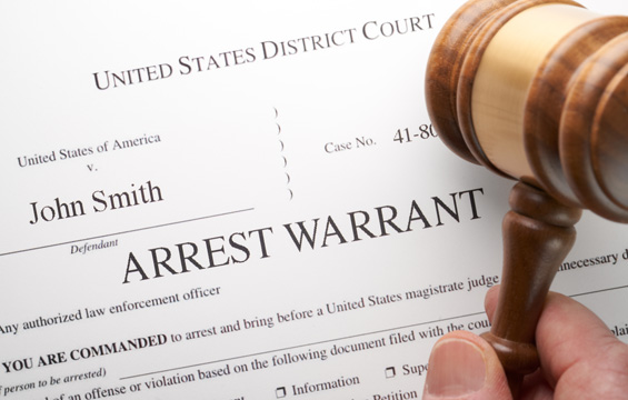 Arrest Warrant document with gavel and hand